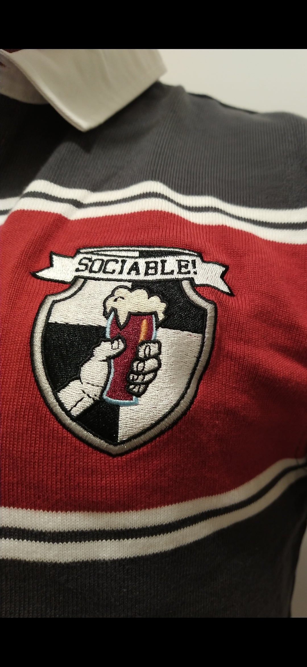 A red and grey rugby shirt with sociable beer crest